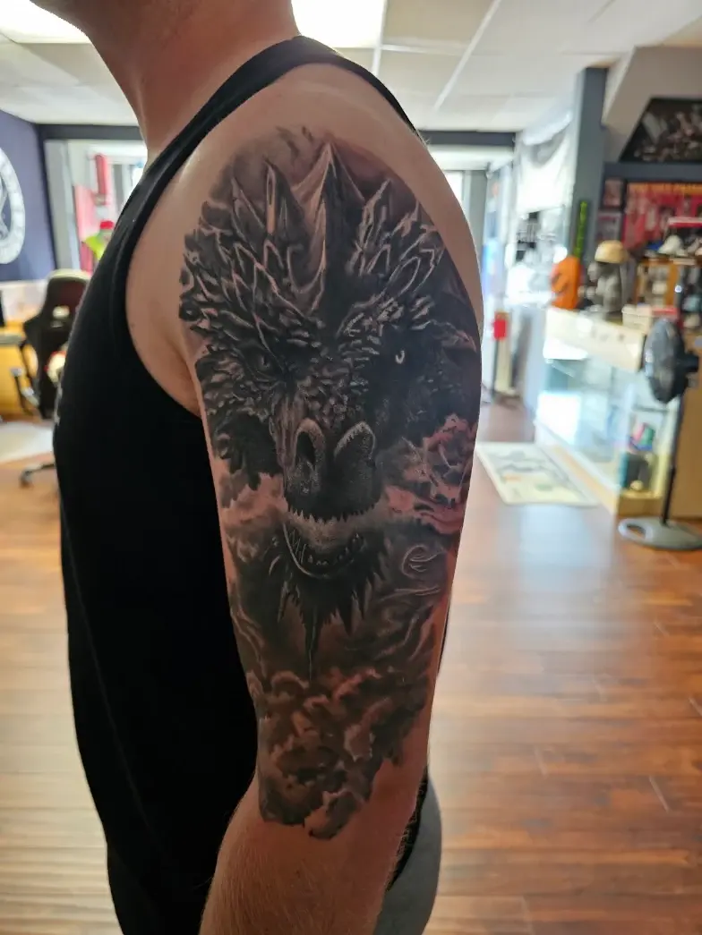 Detailed dark art portrait tattoo covering an upper arm